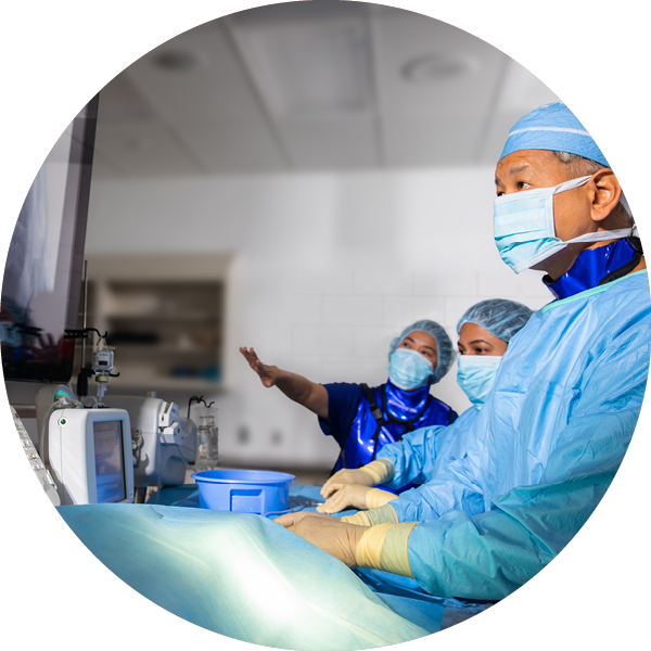 Circle image of a team in surgery looking at a screen.